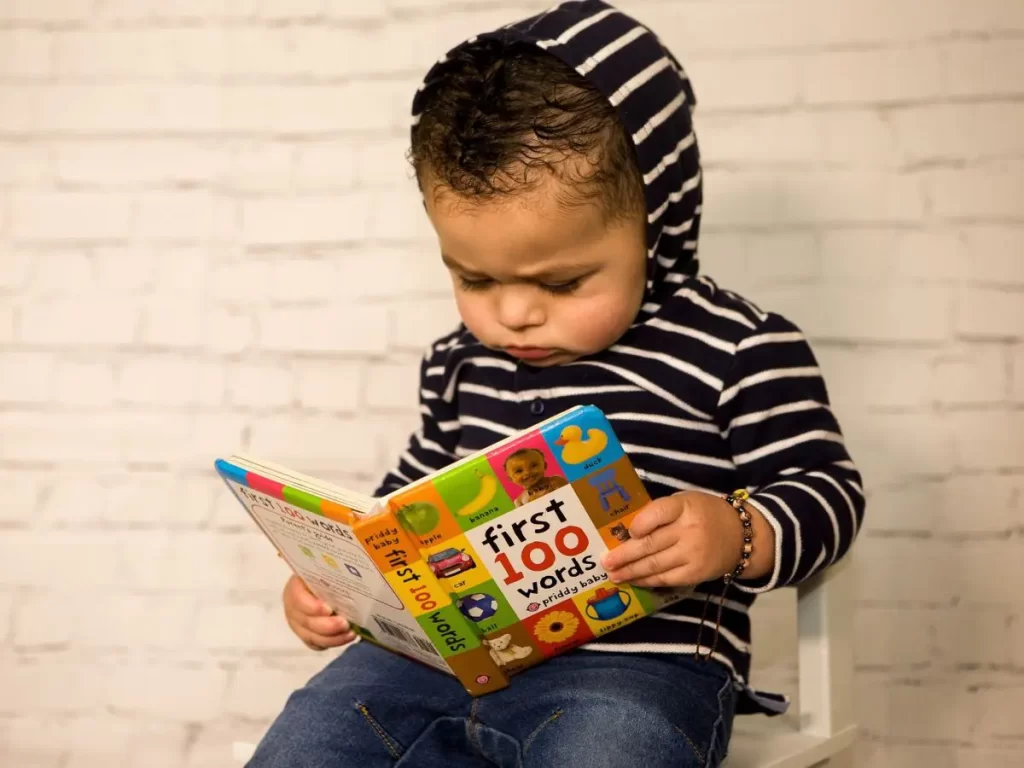Baby reading a book titled first 100 words