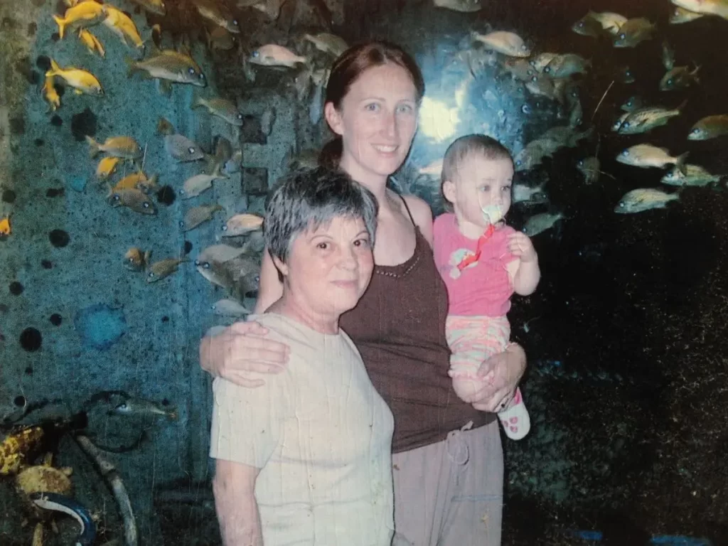grandmother, mother and granddaughter standing together in front of aquarium