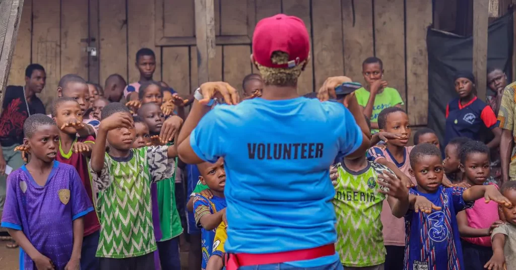 A volunteer standing in front of a group of kids with her hands on her shoulder