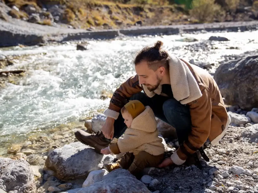 Dad showing baby something in nature near a river