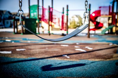 a swing in a park with a play structure in the background