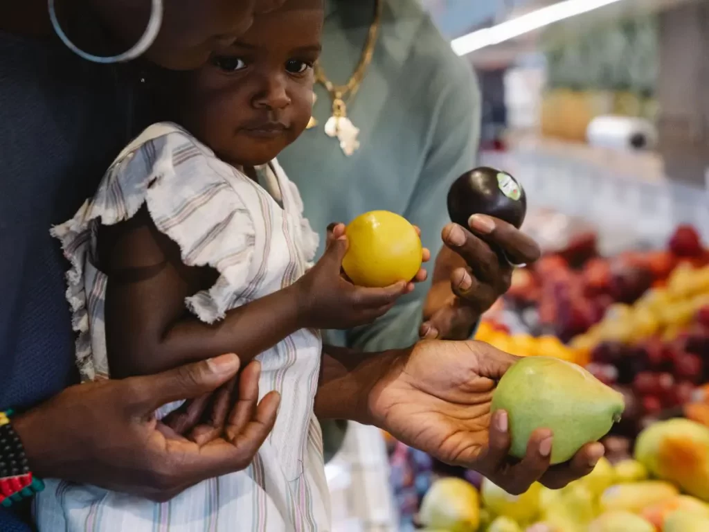 parents grocery shopping with child. Child holding a lemon. Grocery shopping with kids blog post picture