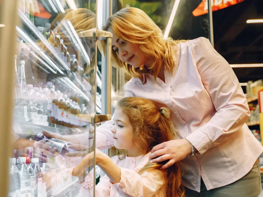 mom and child looking at food label while grocery shopping.