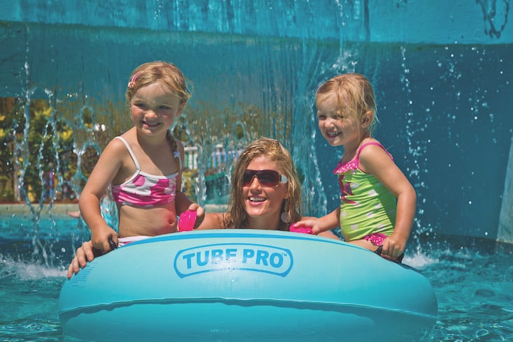 Solo parent travel mom in inner tube with her two children in a pool