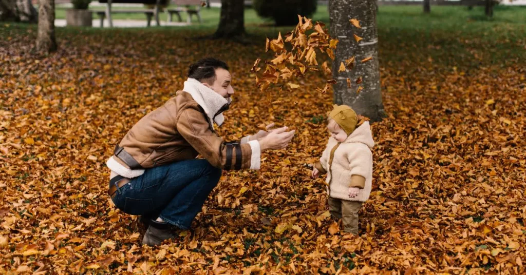 dad throwing fall leaves on child