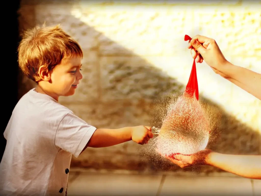 Kid trying to stay cool this summer by popping a water balloon