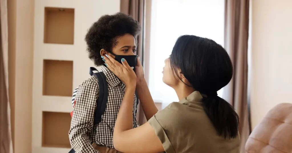 a mother holding a child's face wearing a mask getting ready to go back to school during covid