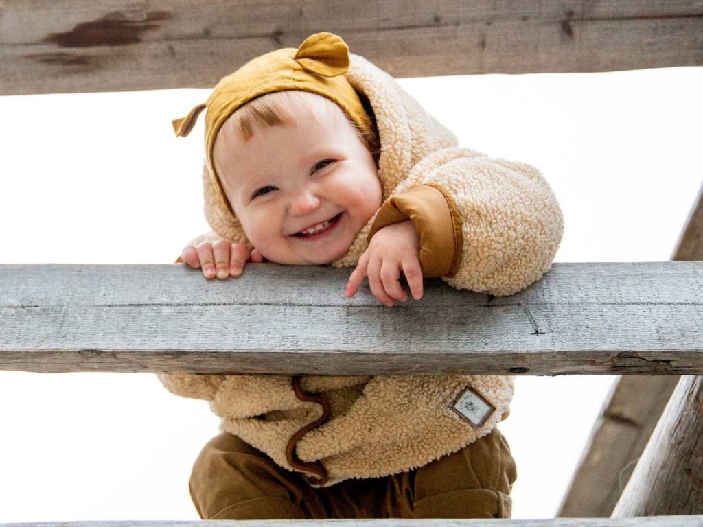 baby with a playful smile trying to sign with fingers