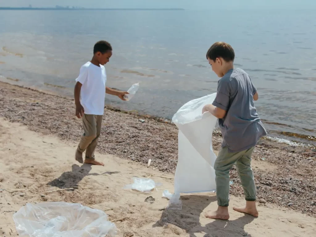 Two children cleaning up garbage on the beach