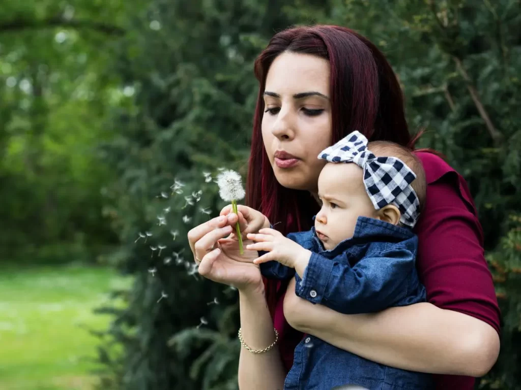 Mom blowing a flower with baby