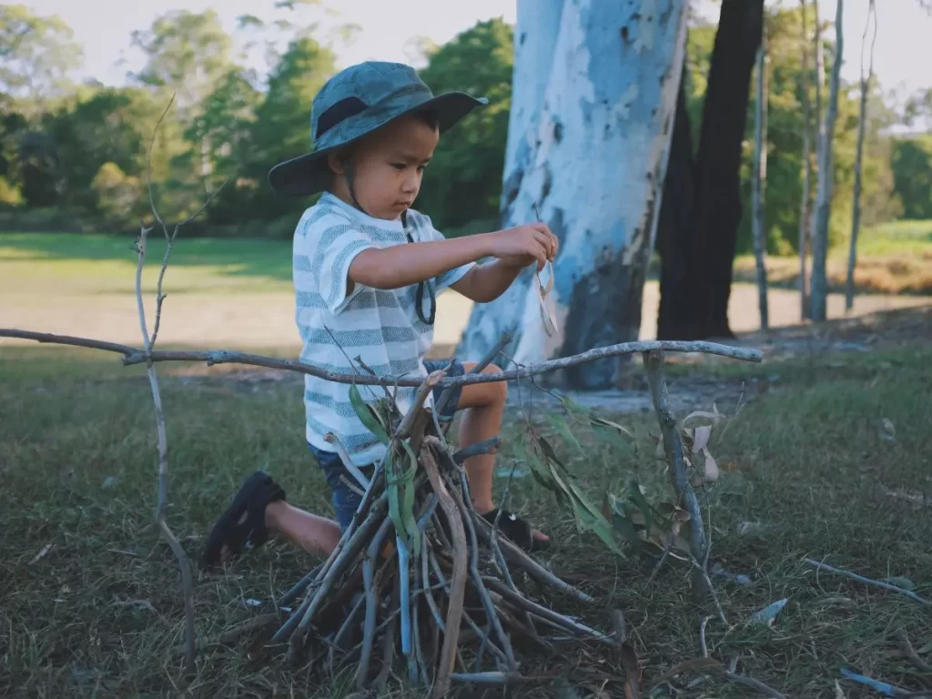 A child building a fire with sticks. 