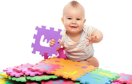 baby sitting with alphabet letters holding the letter E
