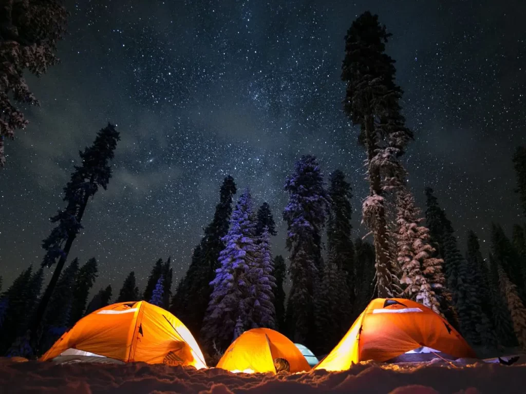 three orange tents with a star filled sky above. 