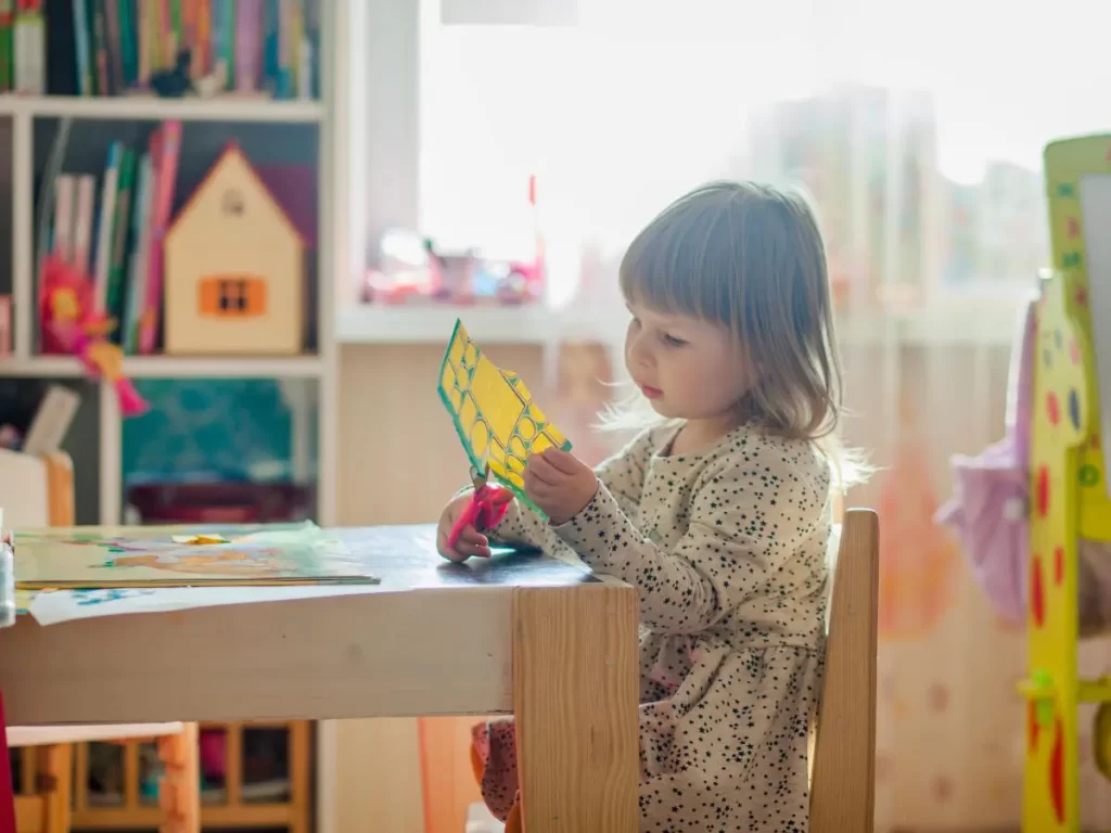 child sitting at a table cutting a piece of paper