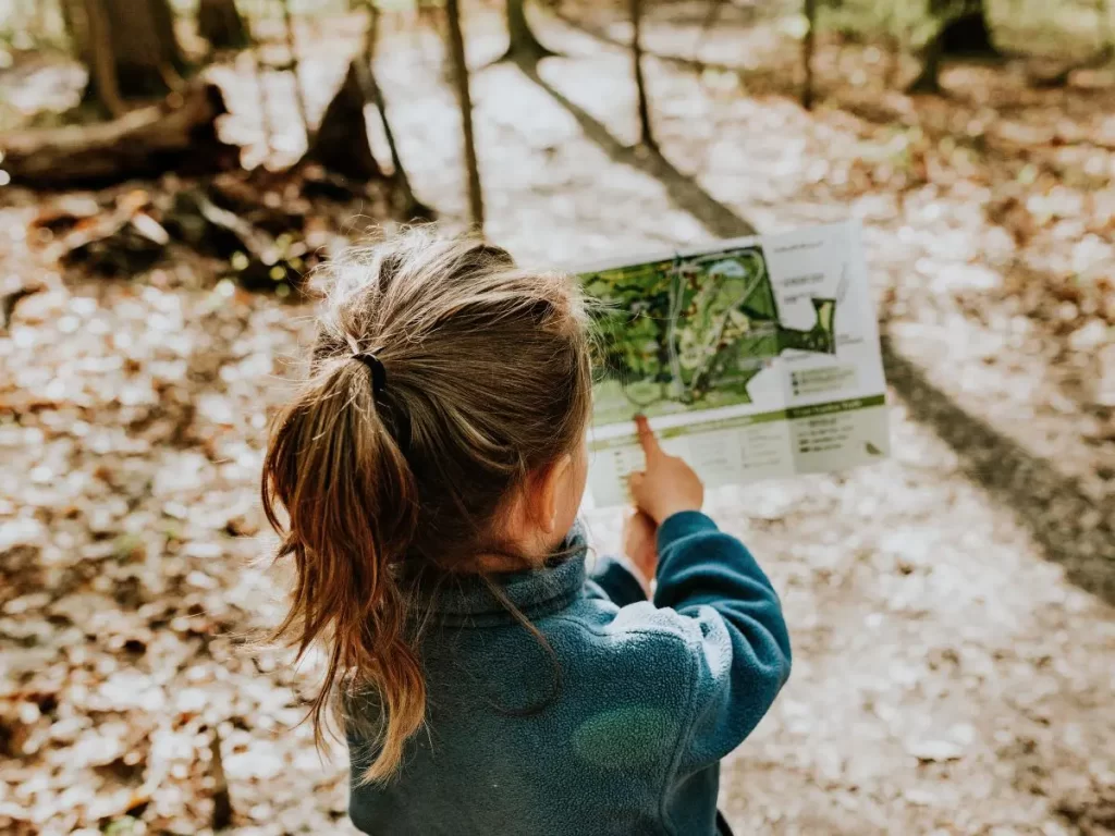 child reading a map while camping