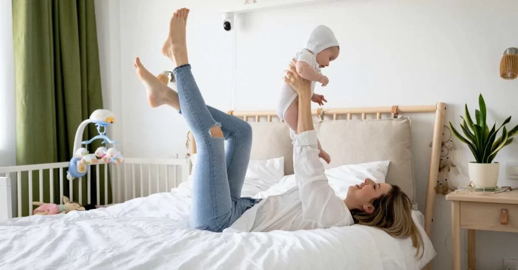 mom lifting baby while lying on bed