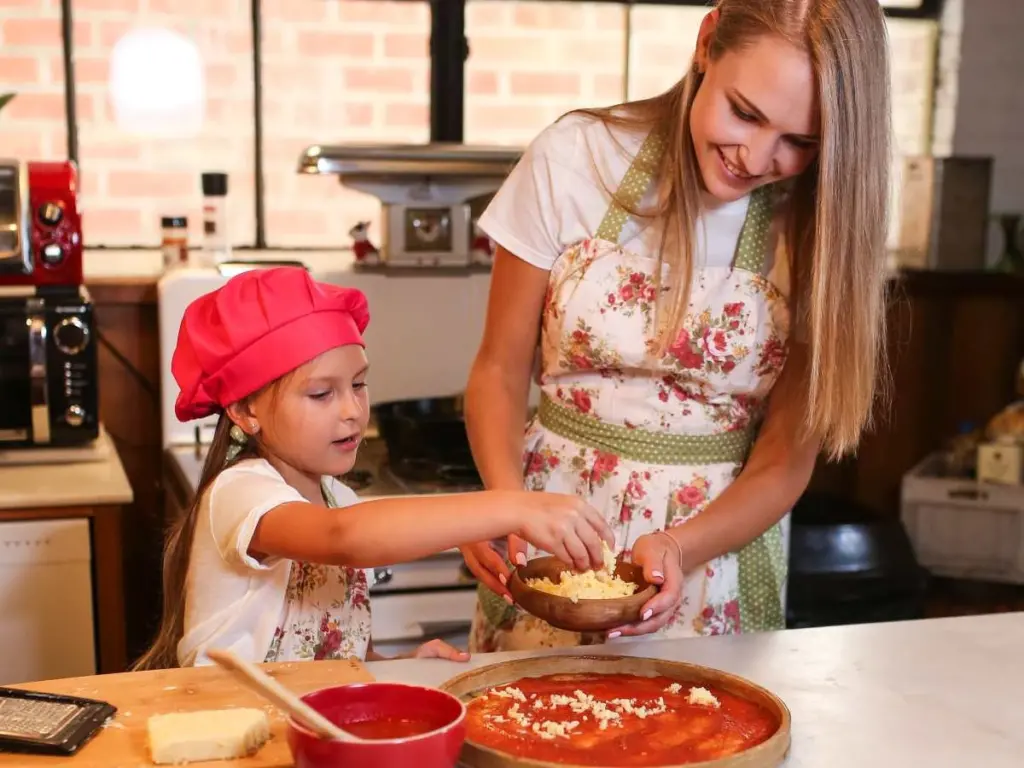 kid and mom making pizza in the kitchen